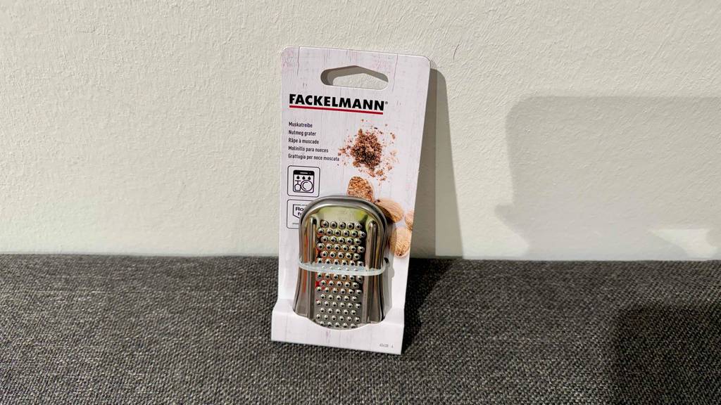 Eine Muskatreibe im Test lehnt in der Verpackung vor einer weißen Wand.