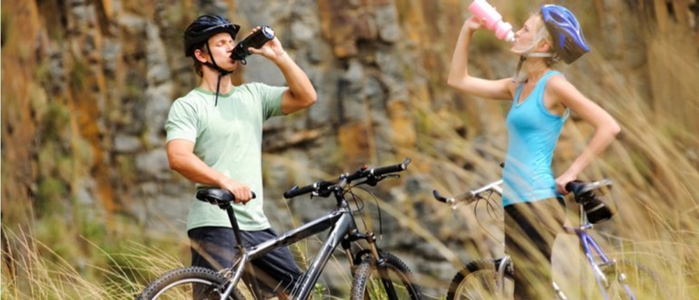 Ein Radfahrer-Paar macht eine Trinkpause mit einer Fahrradtrinkflasche.