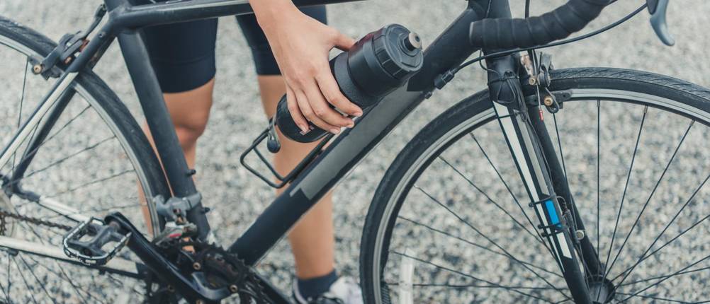 Fahrrad-Flaschenhalter-Test: Frau nimmt Flasche seitlich aus der Halterung