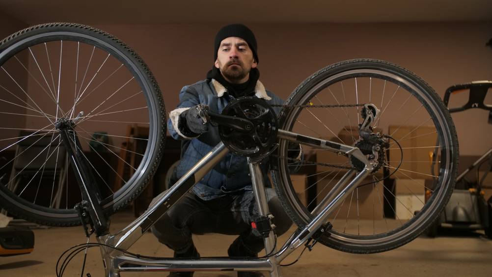 Ein Mann repariert sein Fahrrad und nimmt Anpassungen vor.