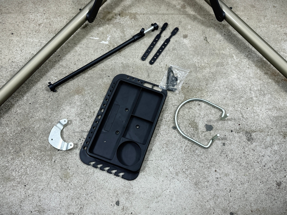 Der komplette Lieferumfang des Cxwxc Fahrrad-Montageständers auf dem Boden ausgebreitet, inklusive Werkzeugablage und Zubehör.