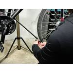 Eine Person befestigt eine Stütze am Cxwxc Fahrrad-Montageständer, um das Vorderrad zu stabilisieren.