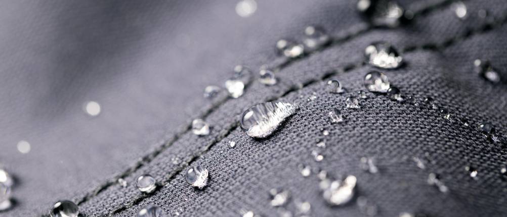 Wasserdichter grauer Stoff zeigt Regentropfen
