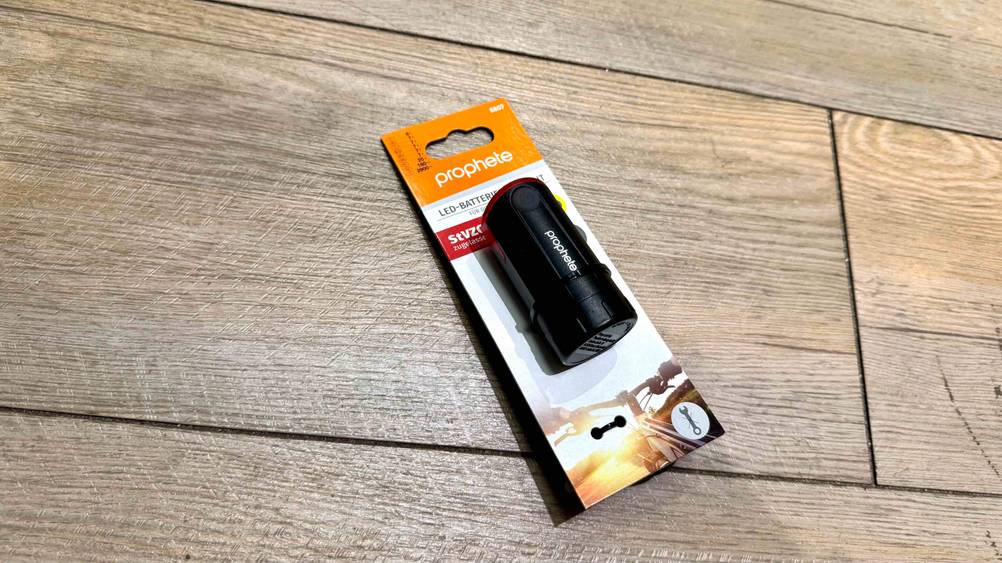 Fahrrad-Rücklicht Batterie-Test: Auf einem Holzboden liegt ein verpacktes Gerät.