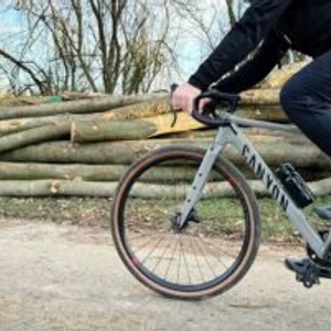Ein Radfahrer fährt mit einer BBB Cycling Wasserflasche am Unterrohr befestigt durch eine ländliche Umgebung. Die Flasche bleibt während der Fahrt stabil in der Halterung.