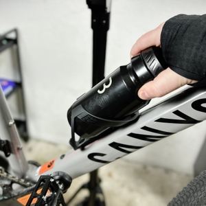 Eine Hand zieht die BBB Cycling Wasserflasche aus der Halterung, wobei sichtbare Kratzer an der Unterseite der Flasche erkennbar sind.