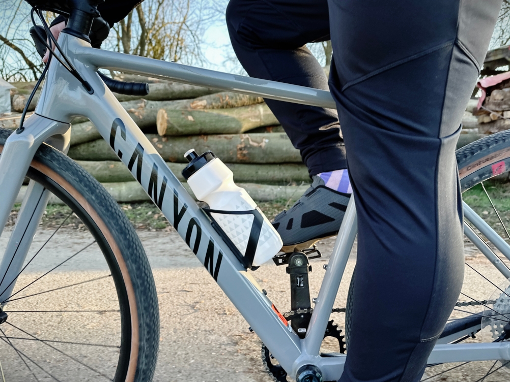 Ein Radfahrer greift während der Fahrt nach der GEMFUL GF001 Trinkflasche. Das Fahrrad ist auf einem Schotterweg unterwegs.