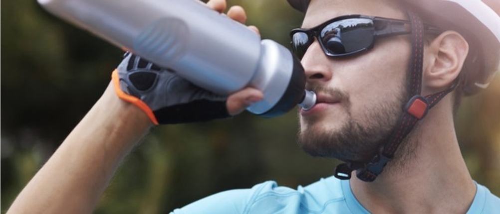 Ein Radfahrer trinkt aus einer Fahrradtrinkflasche.