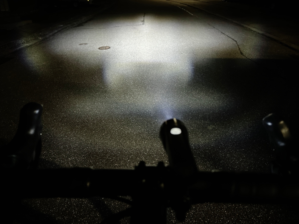 Das Cateye GVolt 60 leuchtet eine dunkle Straße aus. Der Lichtkegel zeigt eine klare Abgrenzung und unterschiedliche Helligkeitsbereiche.