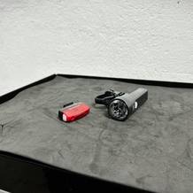 Das Cateye GVolt 60 Set mit Front- und Rücklicht liegt auf einer dunklen Oberfläche. Die Halterung und das Zubehör sind mit abgebildet.