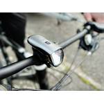 Das Deilin BL12 Frontlicht ist am Lenker eines Fahrrads montiert. Die kompakte Bauweise und die Befestigung sind gut erkennbar.