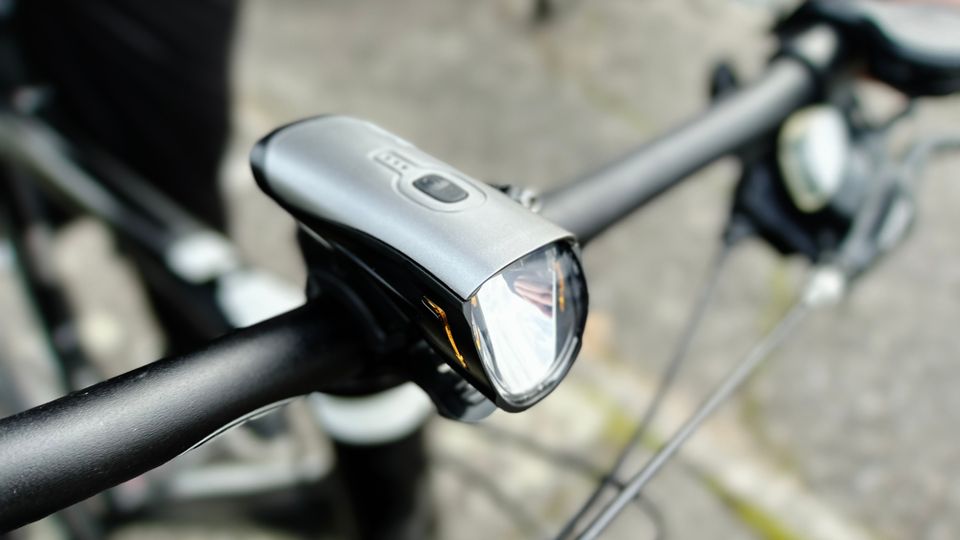 Das Deilin BL12 Frontlicht ist am Lenker eines Fahrrads montiert. Die kompakte Bauweise und die Befestigung sind gut erkennbar.
