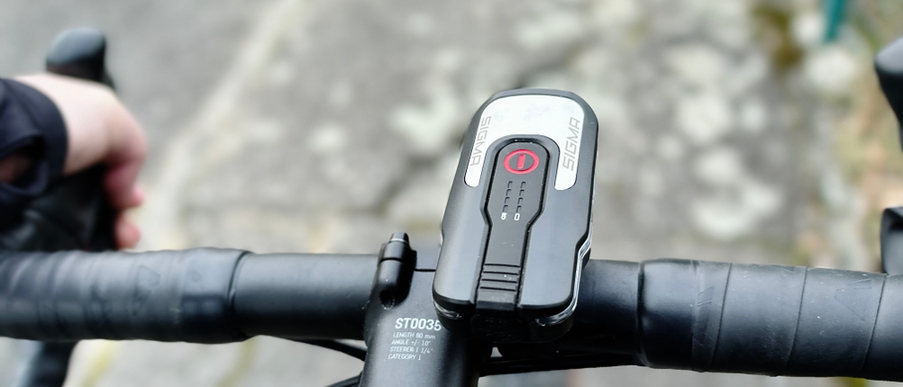 Die Frontleuchte des Sigma Sport Aura 80 Blaze ist am Lenker eines Fahrrads montiert. Die stabile Halterung sorgt für eine sichere Befestigung während der Fahrt.