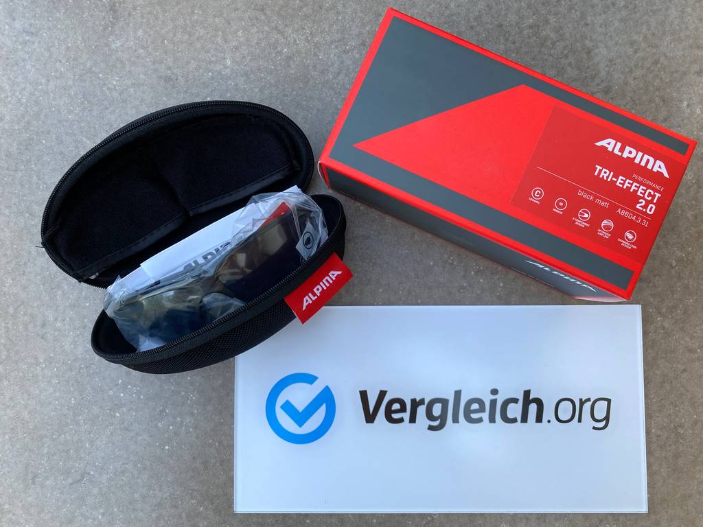 Fahrradbrillen-Test: Fahrradbrille im Etui mit Verpackung und Werbeschild Vergleich.org liegt auf grauem Untergrund