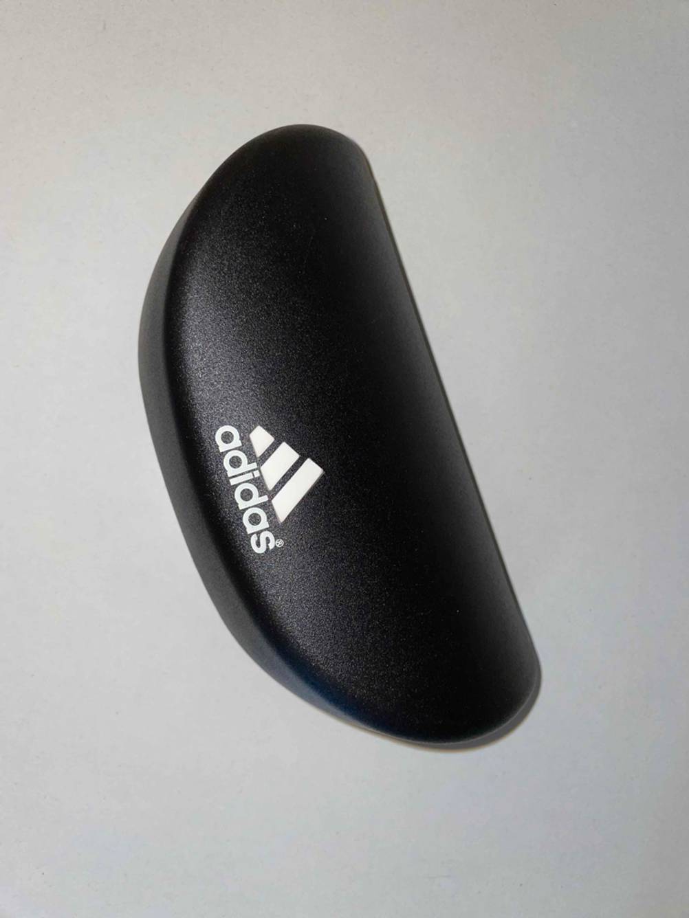 Fahrradbrille für Brillenträger getestet: Ein schwarzes Brillenetui von Adidas auf einer hellen Fläche.