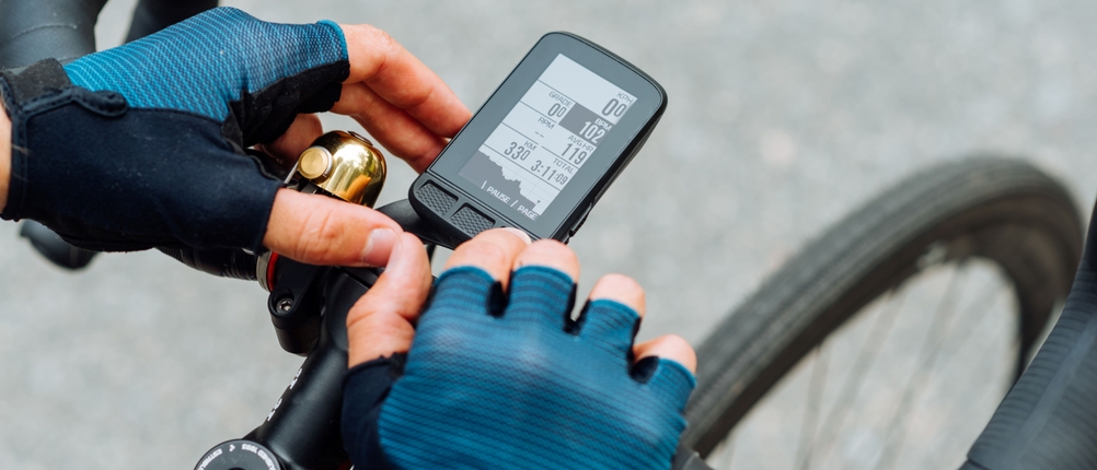 Ein Fahrradcomputer wird mit behandschuhten Händen bedient.