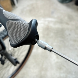 Ein ergonomischer Fahrradgriff wird außen mit einem Schraubendreher fixiert. Die Schraube sitzt in der äußeren Klemme.