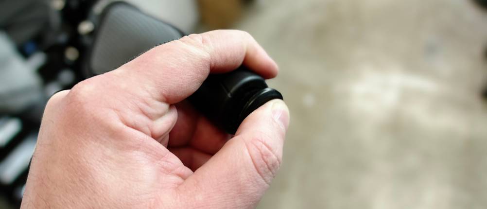 Eine Endkappe wird mit der Hand auf den Lenker eines Fahrrads gesetzt. Der Griff ist bereits montiert.