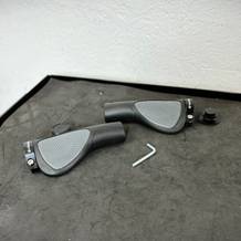 Zwei Topcabin Fahrradgriffe liegen samt Zubehör und Inbusschlüssel auf einer schwarzen Unterlage. Die Oberfläche der Griffe ist gut erkennbar.