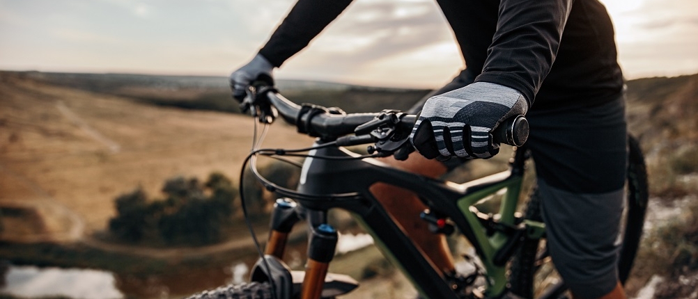 fahrradhandschuhe-erwachsene-test: ein Mann auf dem Mountainbike ist auf einer Tour durch die Berge und trägt graue Fahrradhandschuhe