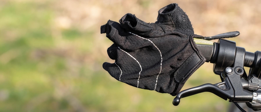 Fahrradhandschuhe-Erwachsene-Test: ein schwarzer Fahrradhandschuh mit kurzen Fingern und Klettverschluss hängt an einem Lenker
