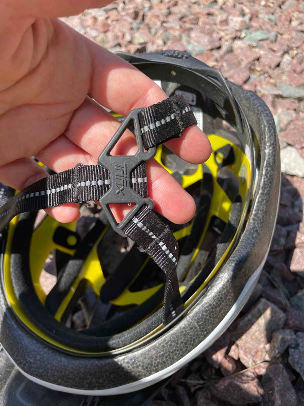 Fahrradhelm-Herren-Test: Nahaufnahme der Gurte des Helms von einer Hand gehalten.