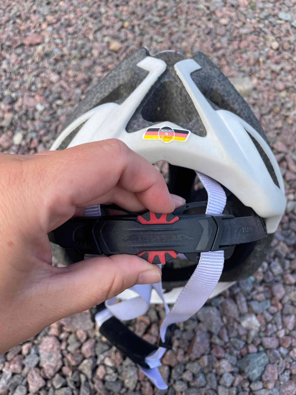 Fahrradhelm-Test: Fahrradhelm, der in der Hand gehalten wird, Fokus auf das Drehrädchen, mit dem Passform eingestellt wird