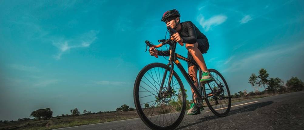 fahrradhose-unisex-test: Ein Mann in Fahrradkluft mit Helm, Fahrradhose und Fahrradshirt radelt eine Straße entlang.