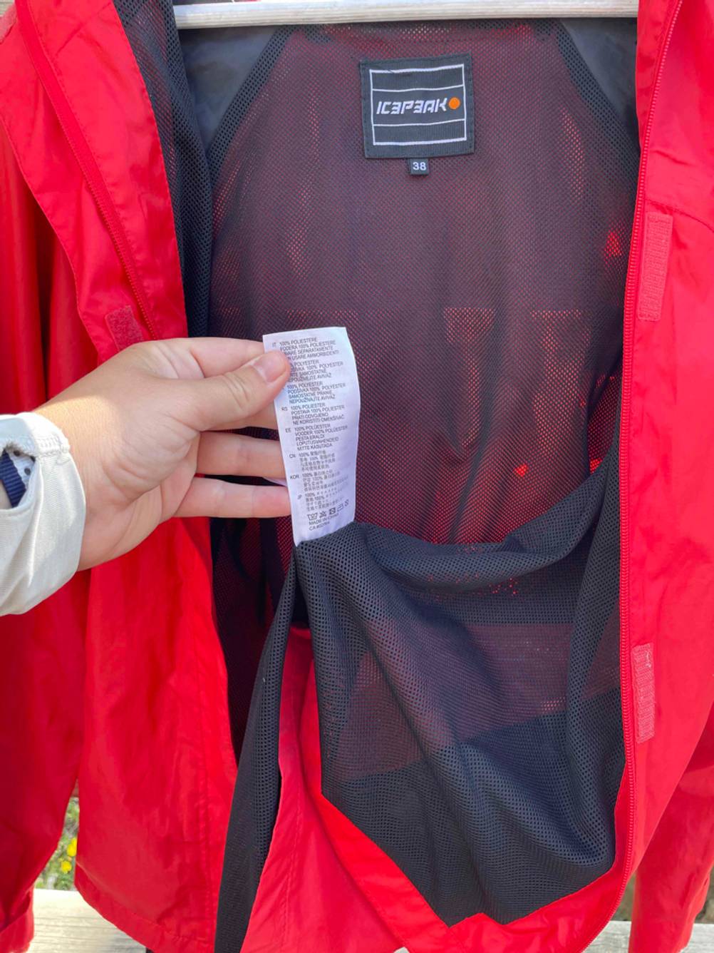 Eine Hand hält das Waschlabel einer getesteten Fahrradjacke.
