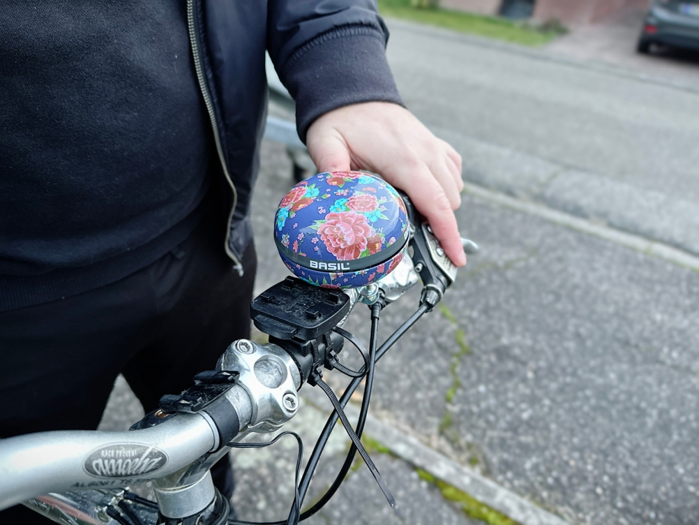 Die Basil Big Bell Bloom ist am Lenker eines Fahrrads montiert. Ihr großes Gehäuse nimmt eine zentrale Position ein.