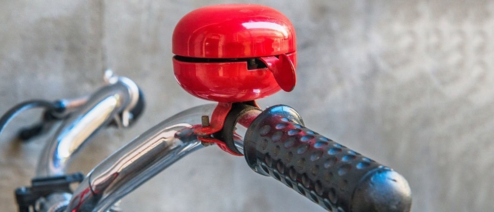 Eine rote Fahrradklingel ist an einem Lenker befestigt.