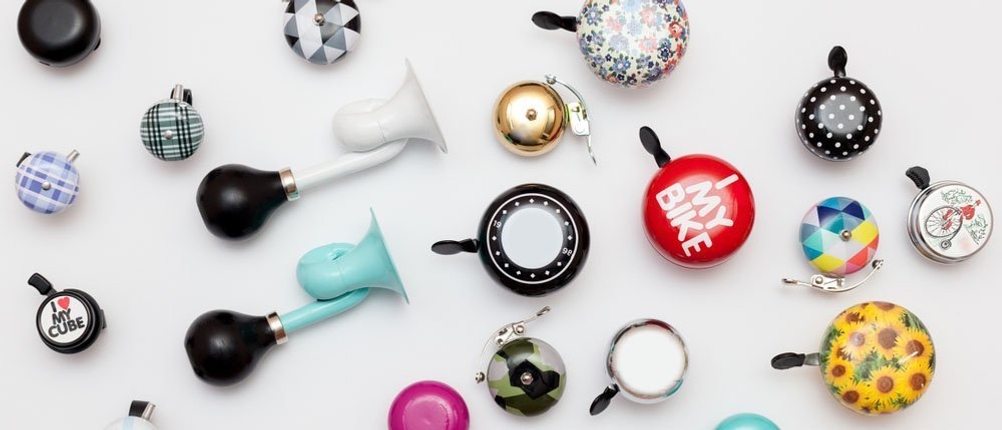 Mehrere unterschiedliche Fahrradklingeln sind auf einer weißen Oberfläche ausgebreitet.