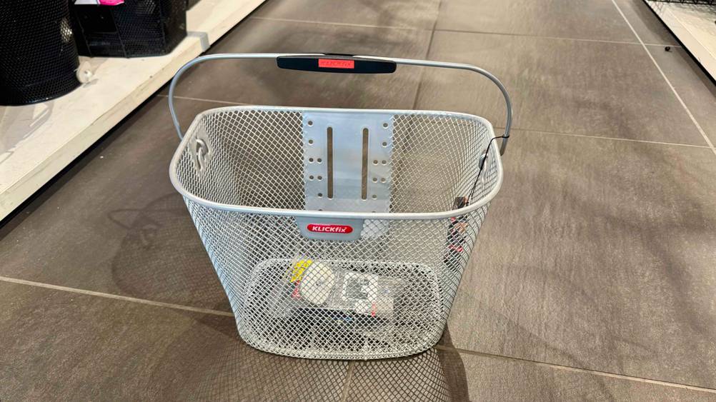 Ein getesteter Fahrradkorb (vorne) steht auf einem Boden.