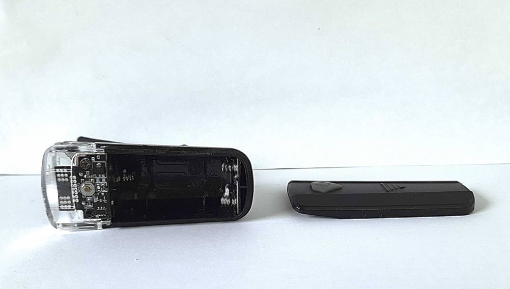 Eine Fahrradlampe Batterie im Test mit geöffnetem Batteriefach und der Abdeckung daneben.