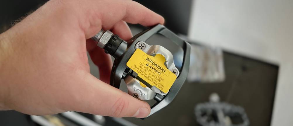 Die Unterseite der Fahrradpedale von Shimano wird in der Hand gehalten und ist im Detail zu sehen.