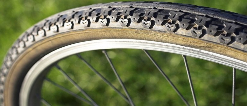 Ein Fahrradreifen in Nahaufnahme vor einer Wiese.