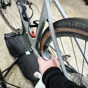 Ein verschmutzter Fahrradrahmen wird mit dem Dr.-Wack-F100-Fahrradreiniger besprüht. Die Szene zeigt den unteren Bereich des Hinterbaus.