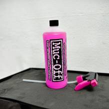 Die Flasche des Muc-Off Fahrradreinigers steht auf einer dunklen Fläche. Der Sprühkopf liegt abgeschraubt daneben.