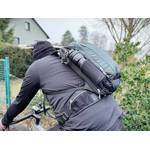 Ein Radfahrer hat einen Fahrradrucksack auf dem Rücken und fährt damit durch eine Ortschaft.