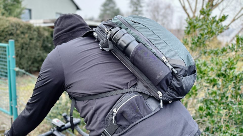 Ein Radfahrer hat einen Fahrradrucksack auf dem Rücken und fährt damit durch eine Ortschaft.