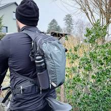 Ein Radfahrer hat einen Fahrradrucksack von Deuter auf dem Rücken. Eine schwarze Flasche steckt in der Seitentasche des Rucksacks.