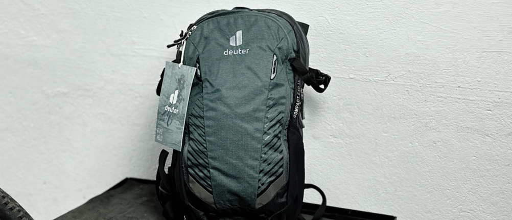 Der Deuter Compact EXP 14 steht aufrecht vor einer weißen Wand. Das Rucksackmodell ist geschlossen und vollständig sichtbar.