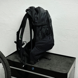 Der Vaude Tremalzo 22 ist seitlich fotografiert und steht aufrecht. Die Gurte und die flache Bauweise sind gut erkennbar.