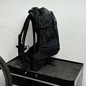 Der Vaude Tremalzo 22 ist seitlich fotografiert und steht aufrecht. Die Gurte und die flache Bauweise sind gut erkennbar.