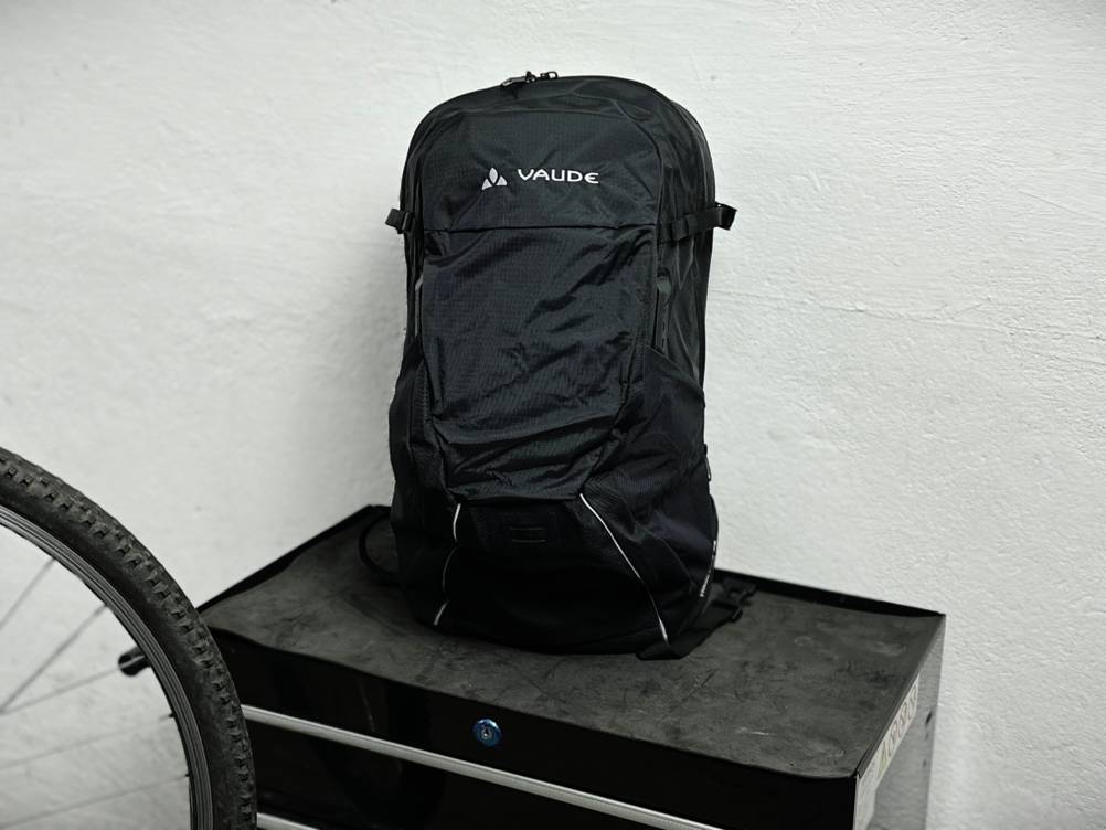 Der Vaude-Tremalzo-22-Fahrradrucksack steht frontal vor einer weißen Wand. Die Reißverschlüsse und das Markenlogo sind gut sichtbar.