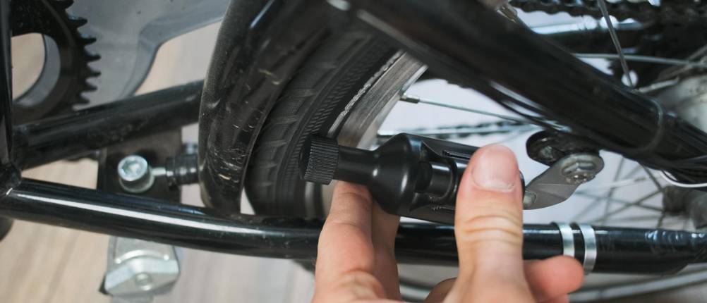 Fahrradscheinwerfer mit Fernlicht im Test: Männerhand drückt Dynamo an den Reifen