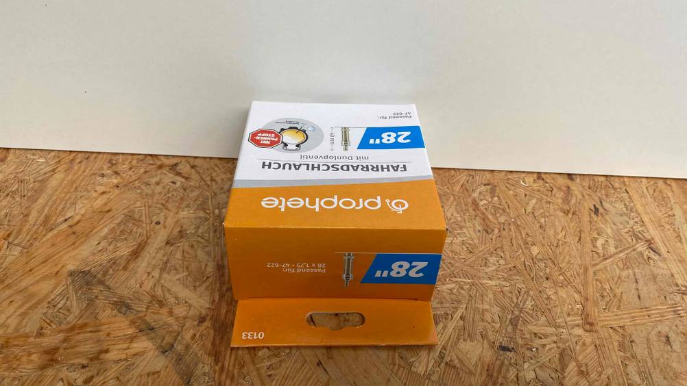 Fahrradschlauch für 28-Zoll große Fahrräder im Test: Auf dem Boden befindet sich die Verpackung von einem Fahrradschlauch für 28-Zoll große Fahrräder. 