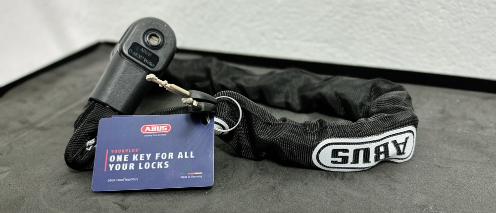 Das Abus CityChain 1010 liegt ausgebreitet auf einer Oberfläche. Ein Schlüssel und eine Codekarte sind mit im Lieferumfang enthalten.