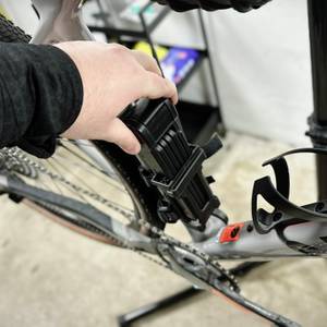 Eine Person zieht das Fischer-Faltschloss aus der am Fahrrad befestigten Halterung. Die Halterung befindet sich nahe der Sattelstütze.