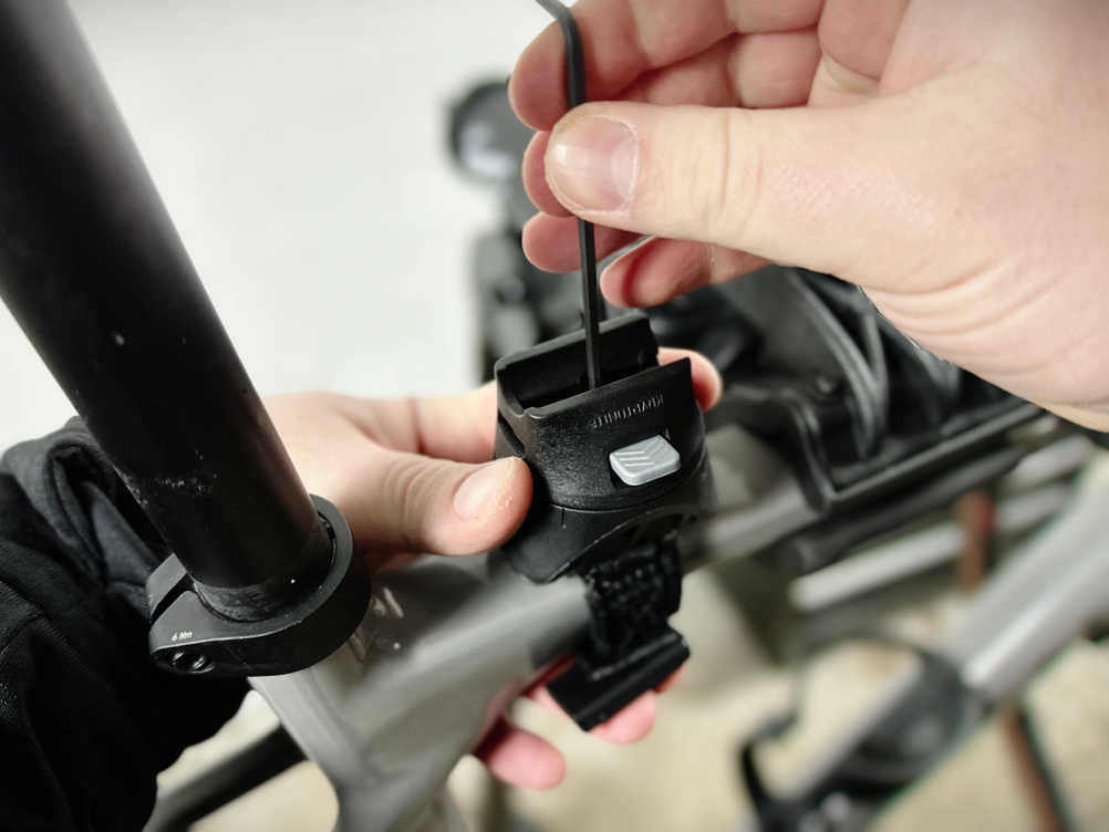 Eine Person montiert die Kryptonite-FlexFrame-Halterung am Fahrradrahmen. Der Halter wird mit einem Innensechskantschlüssel befestigt.